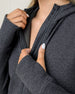 Detail view of a charcoal gray textured hooded jacket showing the fabric, front zipper, collar construction, and thumbhole cuff.