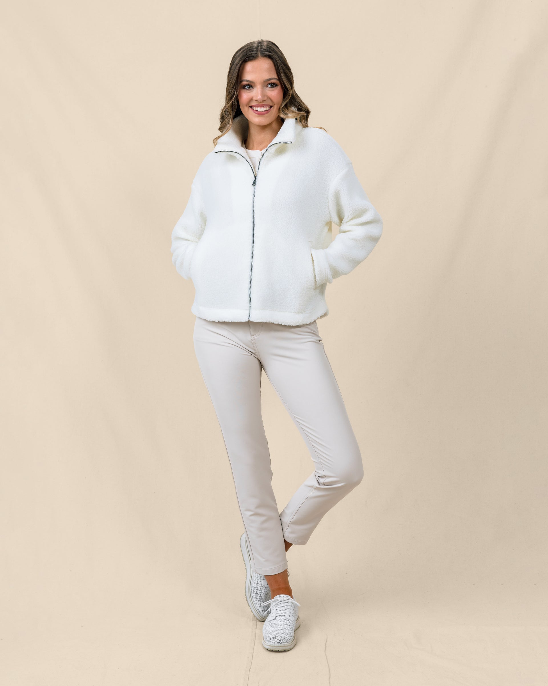 Model wearing the Kemble Fleece Jacket in Coconut zipped with golf pants for a cozy cool-weather outfit