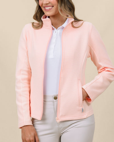 Front view of a model wearing the New Swing Jacket in Melba open over a white polo with light-colored pants.