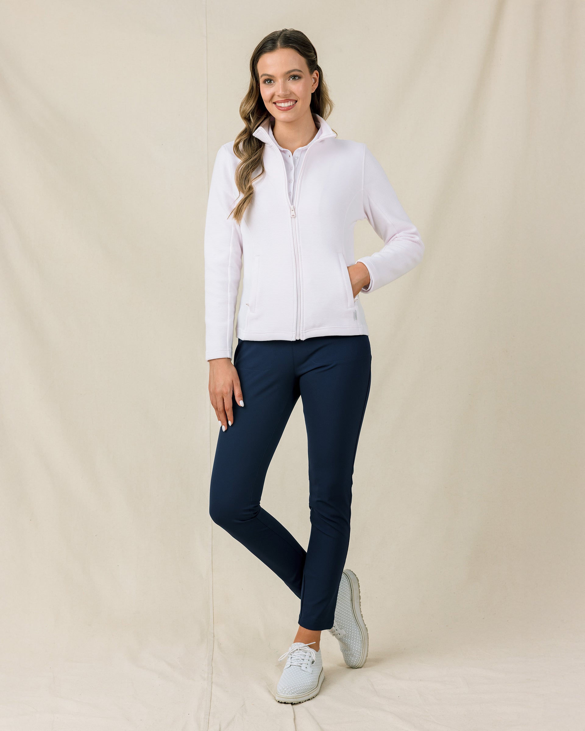 Woman wearing the Straight Down New Swing Jacket in Pale Pink zipped paired with navy golf pants