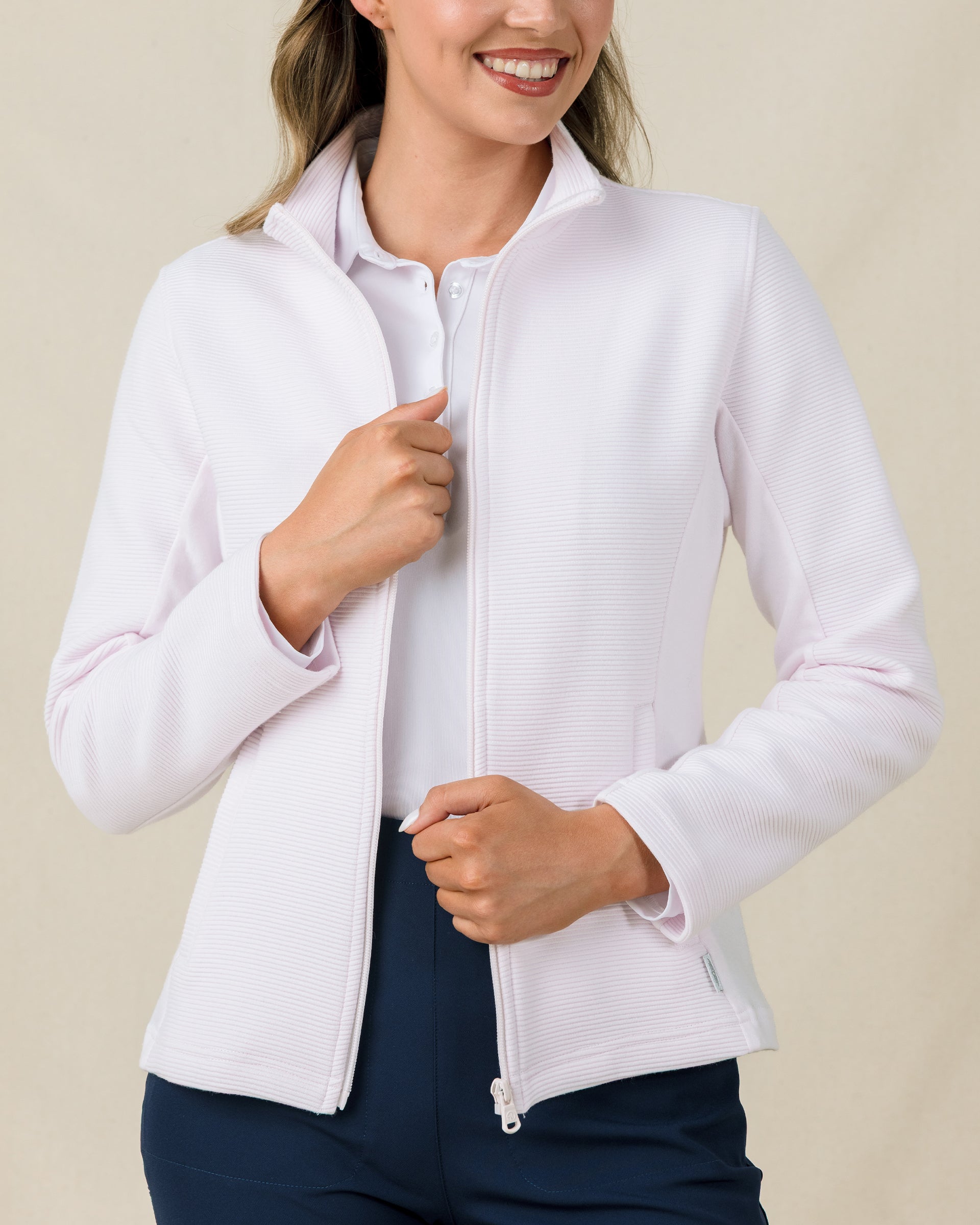 Close-up of the Straight Down New Swing Jacket in Pale Pink worn unzipped over a white polo, showcasing the ribbed texture