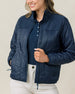 Woman wearing the Taylor Jacket in New Indigo unzipped over a navy golf polo
