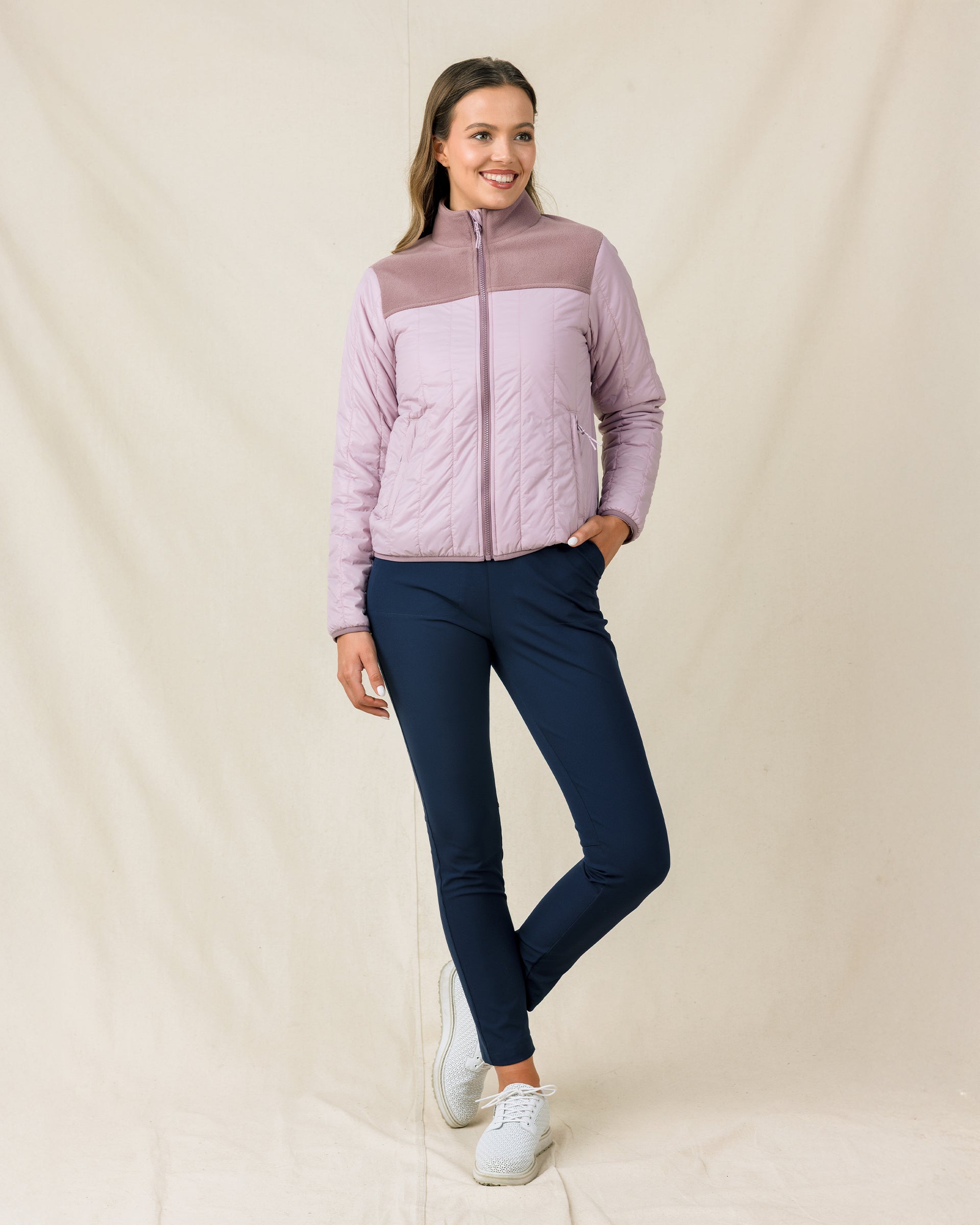 Model wearing the Taylor Jacket in Pink Dawn zipped with navy golf pants