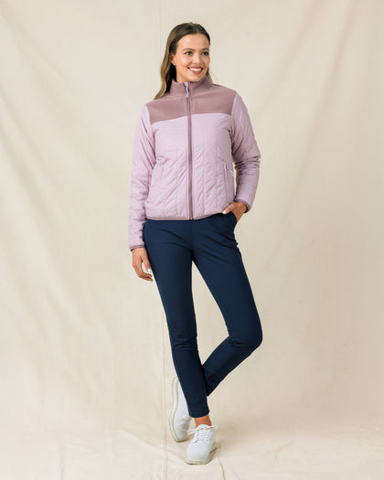 Model wearing the Taylor Jacket in Pink Dawn zipped with navy golf pants
