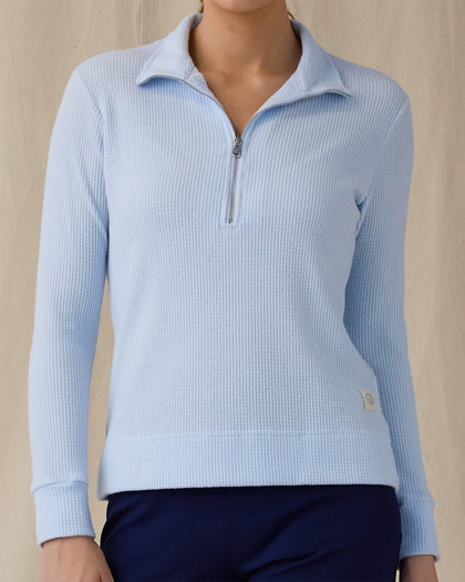 Women's Hills Quarter Zip in Lake, front view on model featuring a light blue waffle-knit quarter-zip pullover with mock neck collar and silver zipper hardware, paired with navy pants