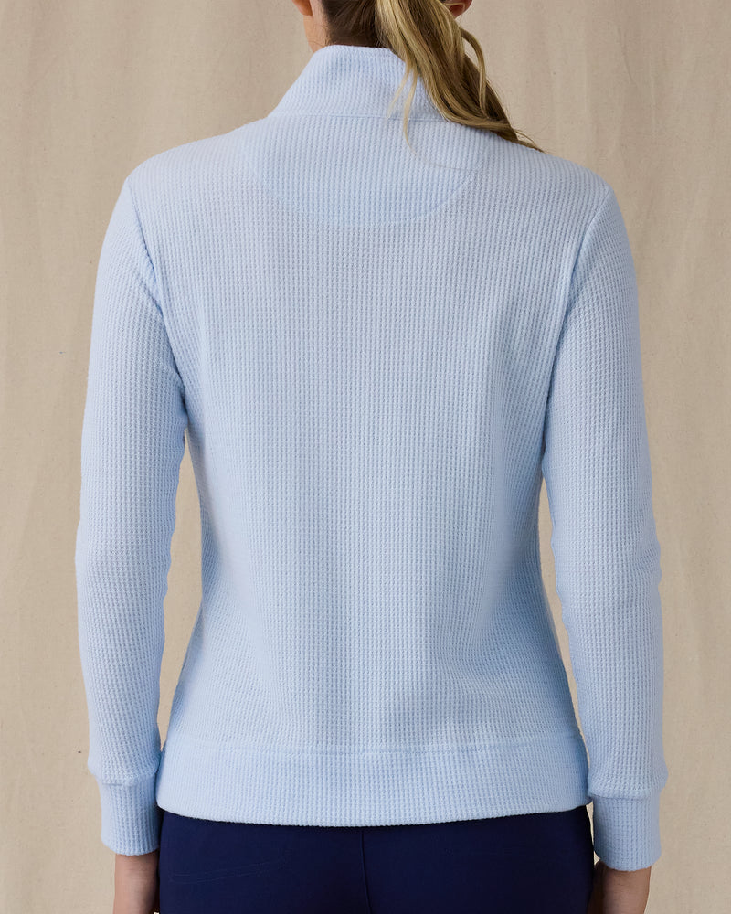 Women's Hills Quarter Zip in Lake, back view on model featuring a light blue waffle-knit quarter-zip pullover with mock neck collar and ribbed cuffs, paired with navy pants