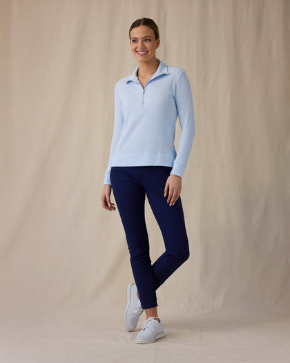 Women's Hills Quarter Zip in Lake, full length front angle view on model featuring a light blue waffle-knit quarter-zip pullover with mock neck collar and Straight Down logo patch at the hem, paired with navy pants and white golf shoes
