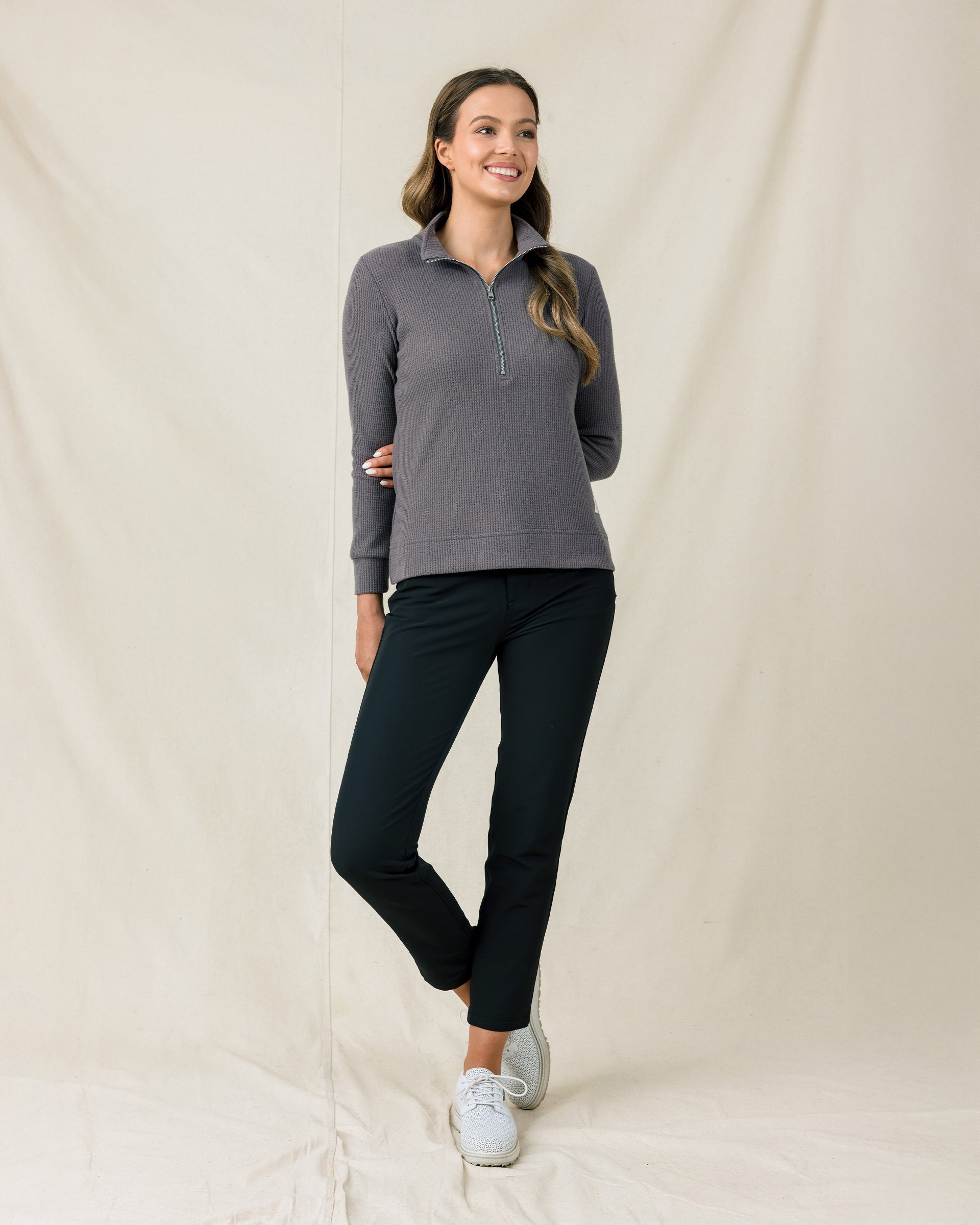 Woman wearing the Hills Quarter Zip in Nightshade with black pants and white golf shoes.