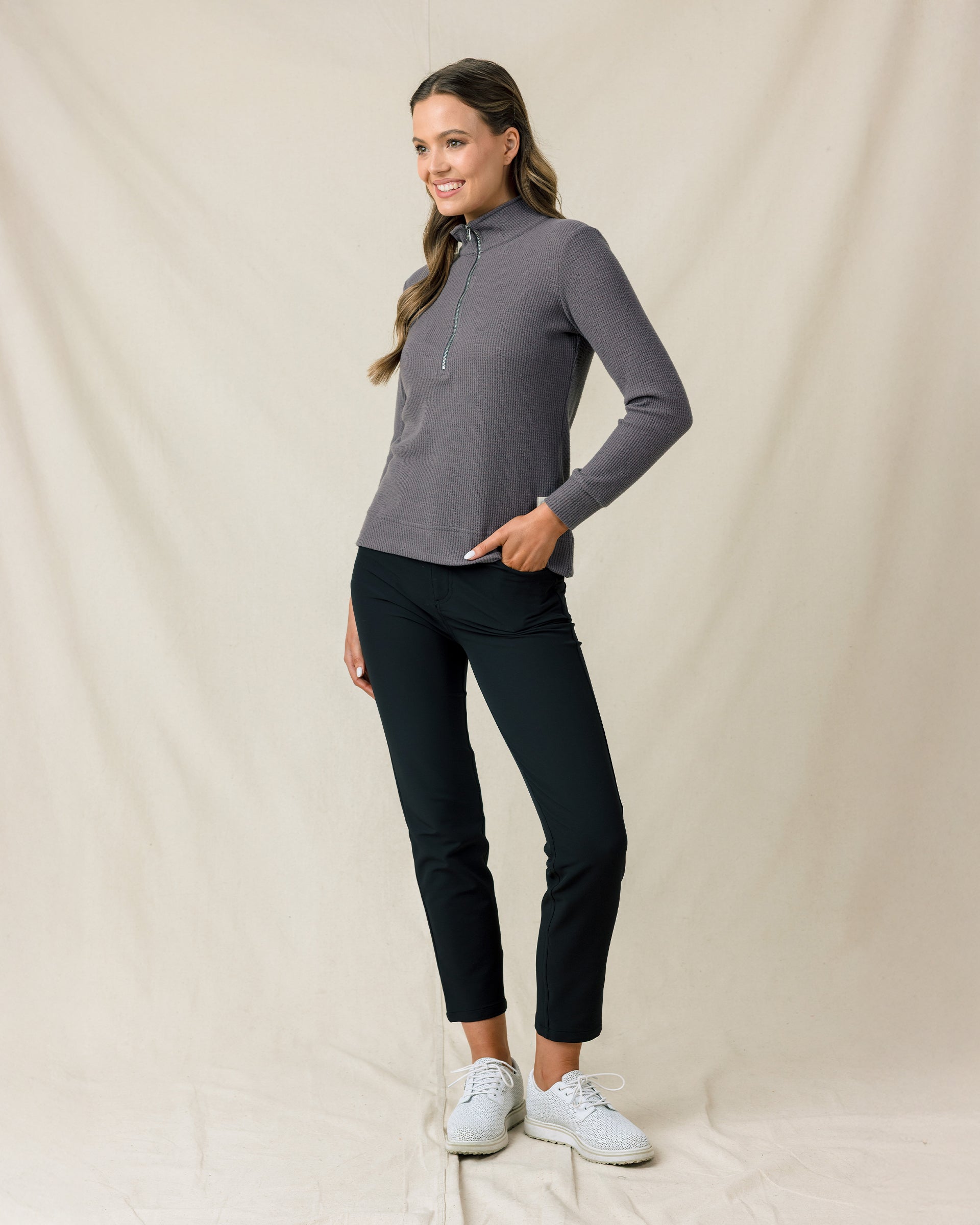 Woman wearing the Hills Quarter Zip in Nightshade, styled with black pants and white golf shoes.