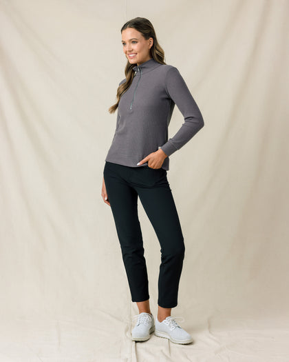 Woman wearing the Hills Quarter Zip in Nightshade, styled with black pants and white golf shoes.