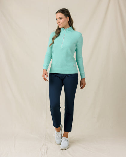 Model wearing the Hills Quarter Zip in Cascade fully zipped with navy pants and white golf shoes