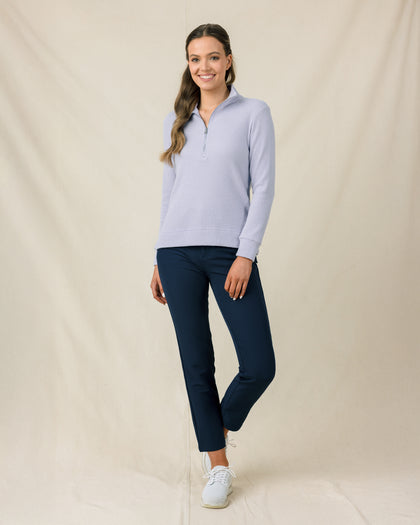 Woman wearing the Straight Down Hills Quarter Zip in Cosmic Blue with the collar open, paired with navy golf pants
