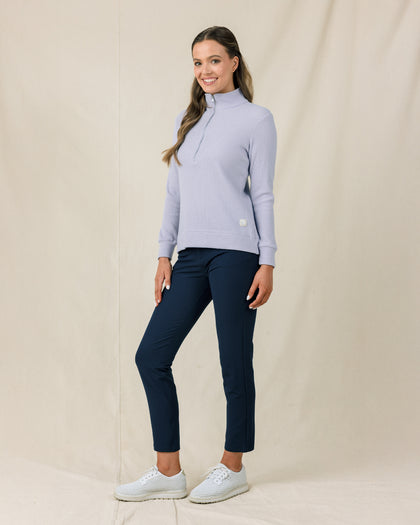 Woman wearing the Straight Down Hills Quarter Zip in Cosmic Blue with the quarter zip fully closed, paired with navy golf pants