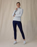 Women's Hills Quarter Zip in New Heather, front full-length view featuring a light heather gray waffle-knit quarter zip pullover with silver zipper and hand gripping zipper pull paired with navy pants and white shoes
