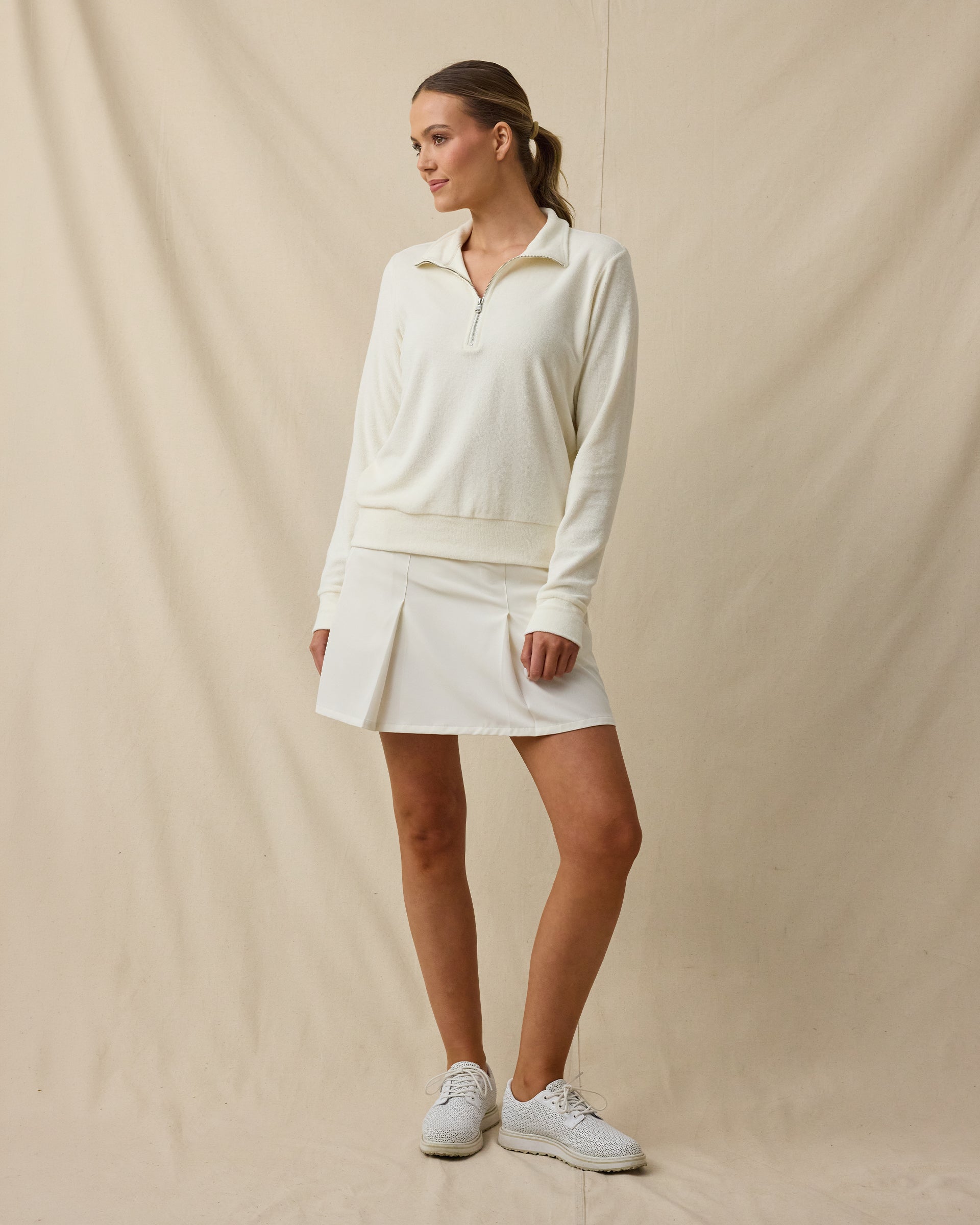 Woman wearing the Collette Quarter Zip in Coconut with a light golf skort