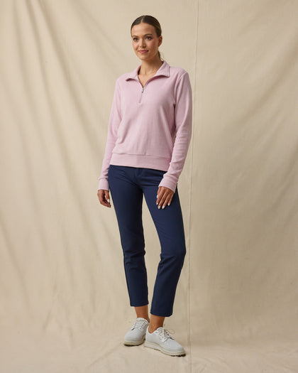 Woman wearing the Collette Quarter Zip in Pink Dawn partially unzipped with navy golf pants