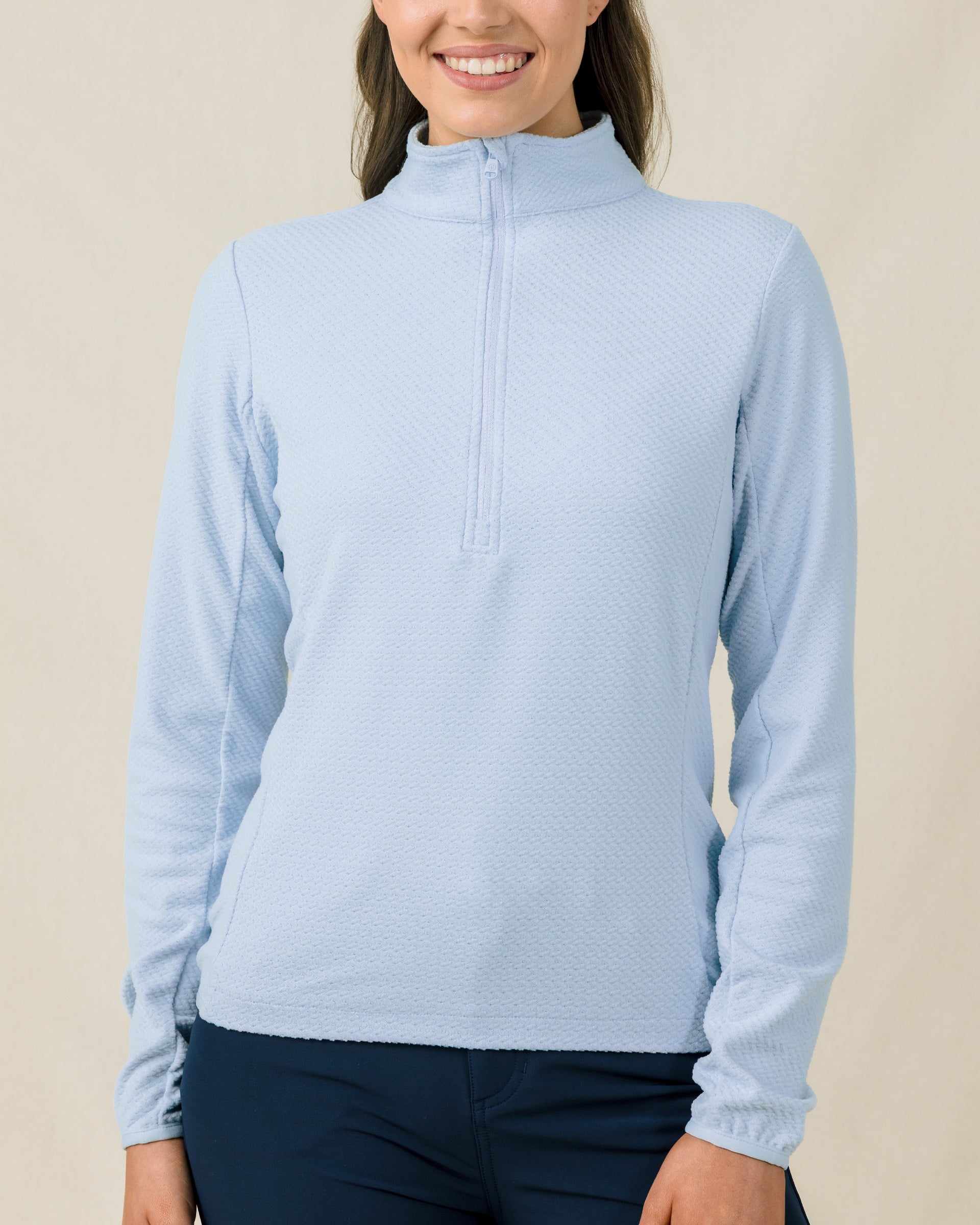 Woman wearing the Lorna Half Zip in Lake, showing the textured fabric, high collar, and streamlined fit.