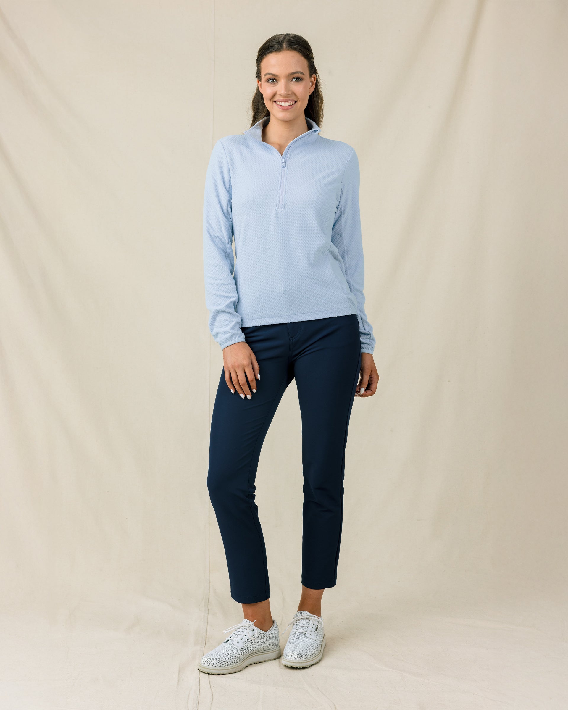 Woman wearing the Lorna Half Zip in Lake with navy pants and white golf shoes.