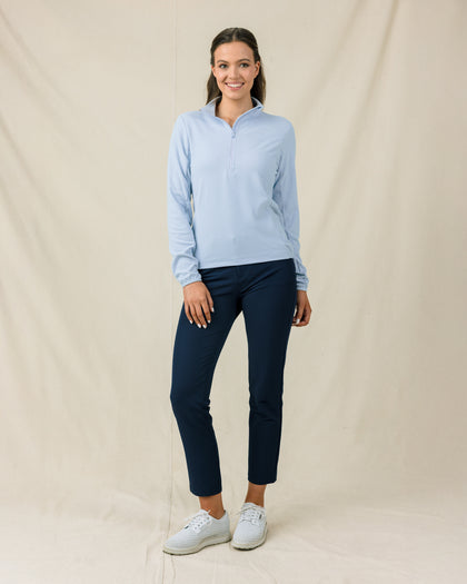 Woman wearing the Lorna Half Zip in Lake with navy pants and white golf shoes.