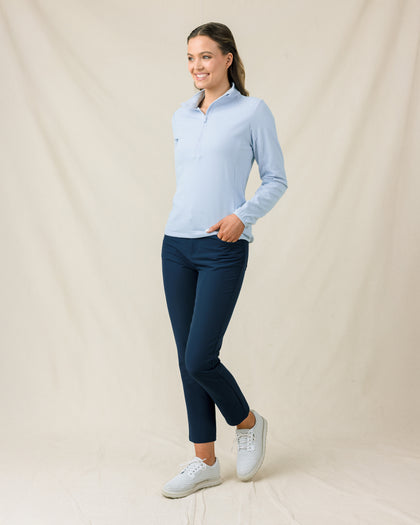 Woman wearing the Lorna Half Zip in Lake, styled with navy pants and white golf shoes.