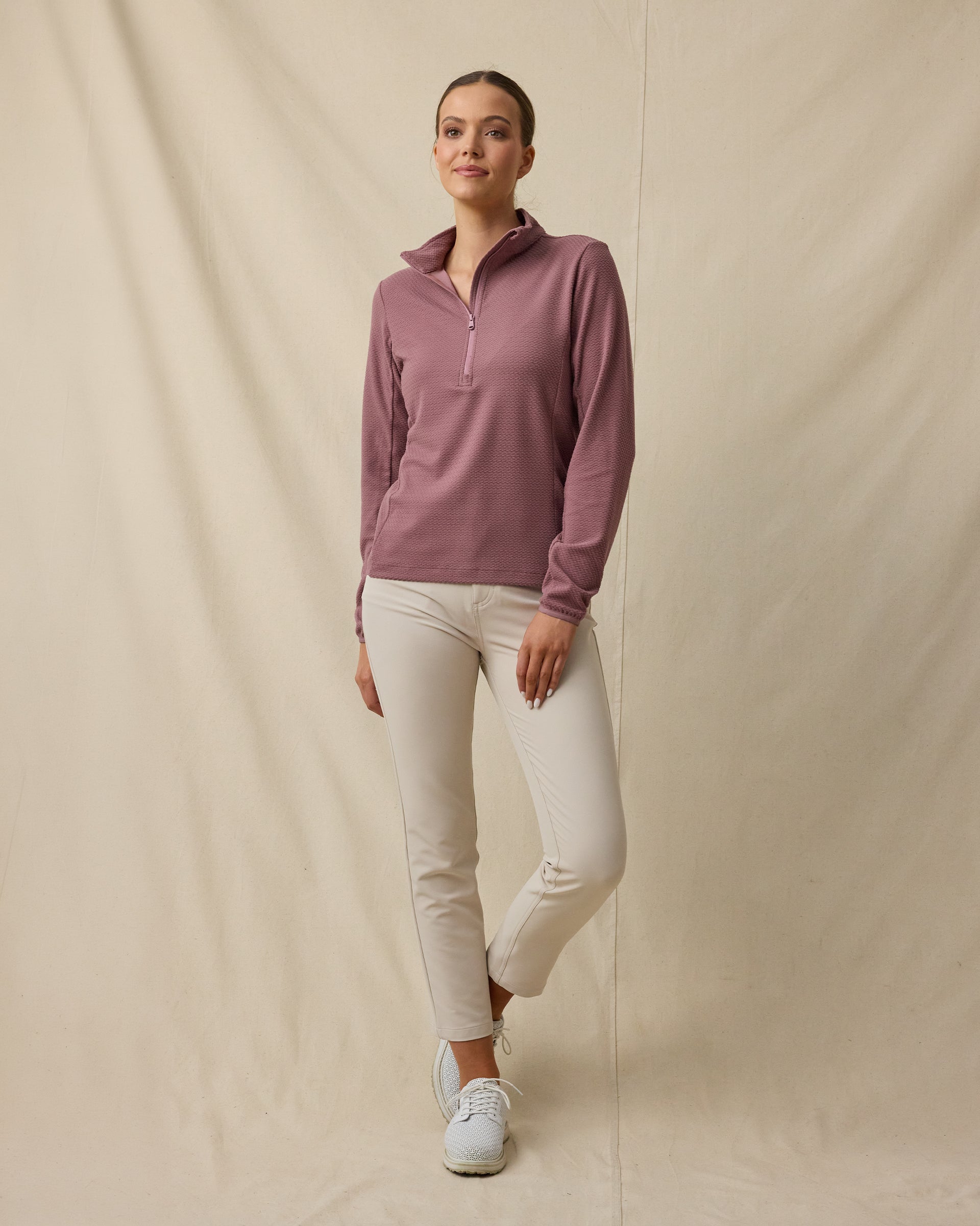Model wearing the Lorna Half Zip in Oxblood Red with cream golf pants, collar unzipped