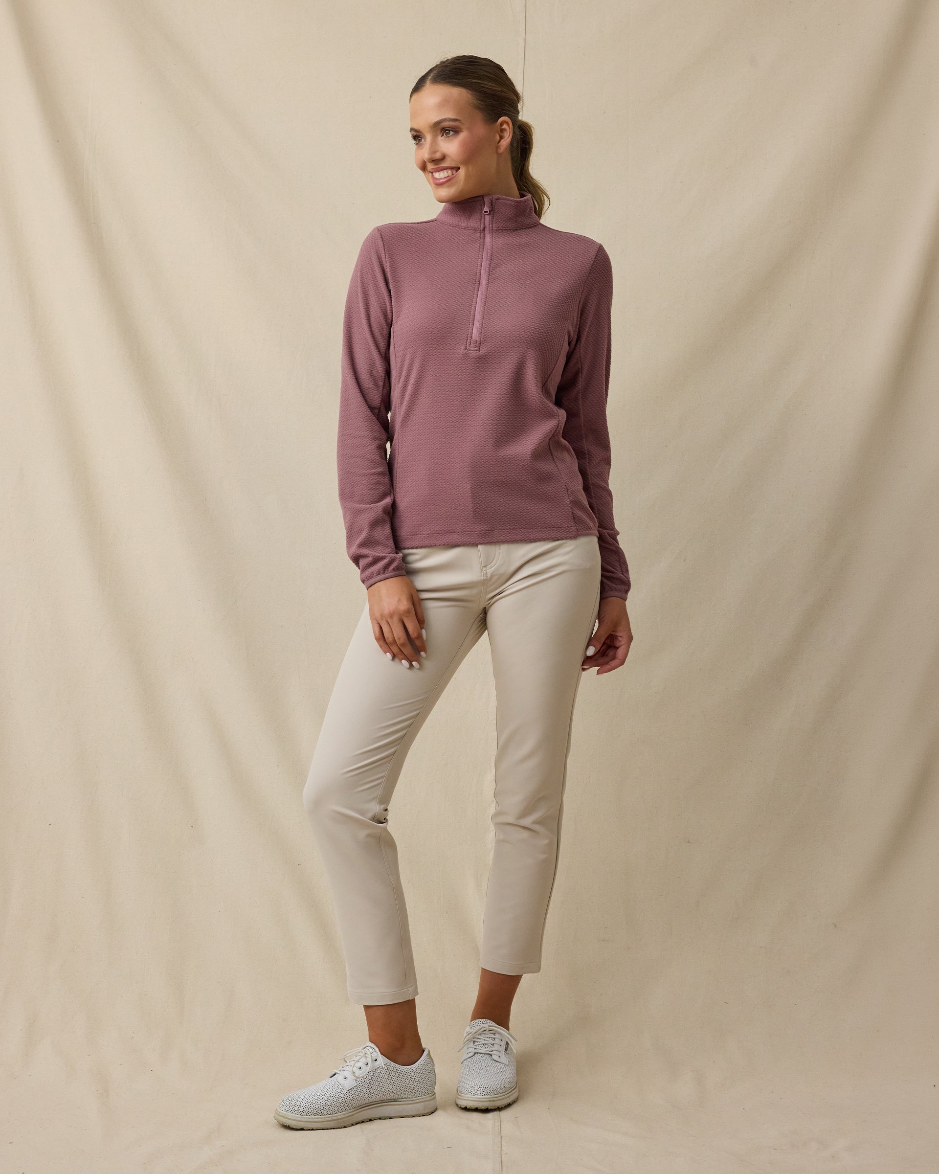 Model wearing the Lorna Half Zip in Oxblood Red with cream golf pants, collar zipped