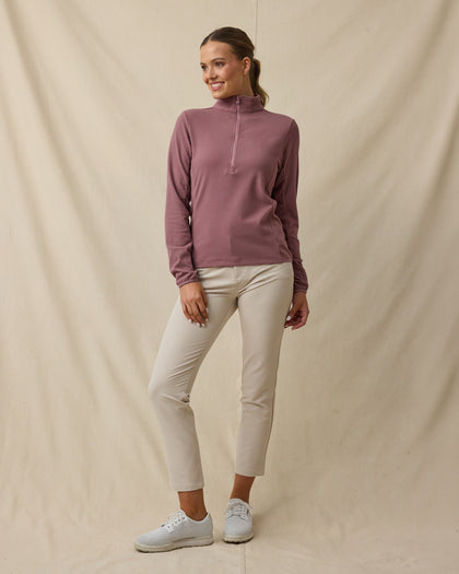 Model wearing the Lorna Half Zip in Oxblood Red with cream golf pants, collar zipped