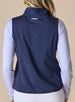 Women's 126th U.S. Open Hestia Vest in New Indigo, back model view featuring a navy quilted sleeveless vest with the Straight Down logo at the back collar layered over a white and blue printed long sleeve top with white pants