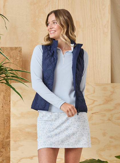 Women's Hestia Vest in New Indigo, front view on model featuring a solid navy quilted diamond pattern styled open over a light blue layer