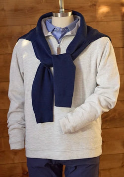 Mannequin styled in a light heather quarter-zip pullover layered over a striped polo, with a navy sweater draped over the shoulders and navy trousers for a classic heritage-inspired look